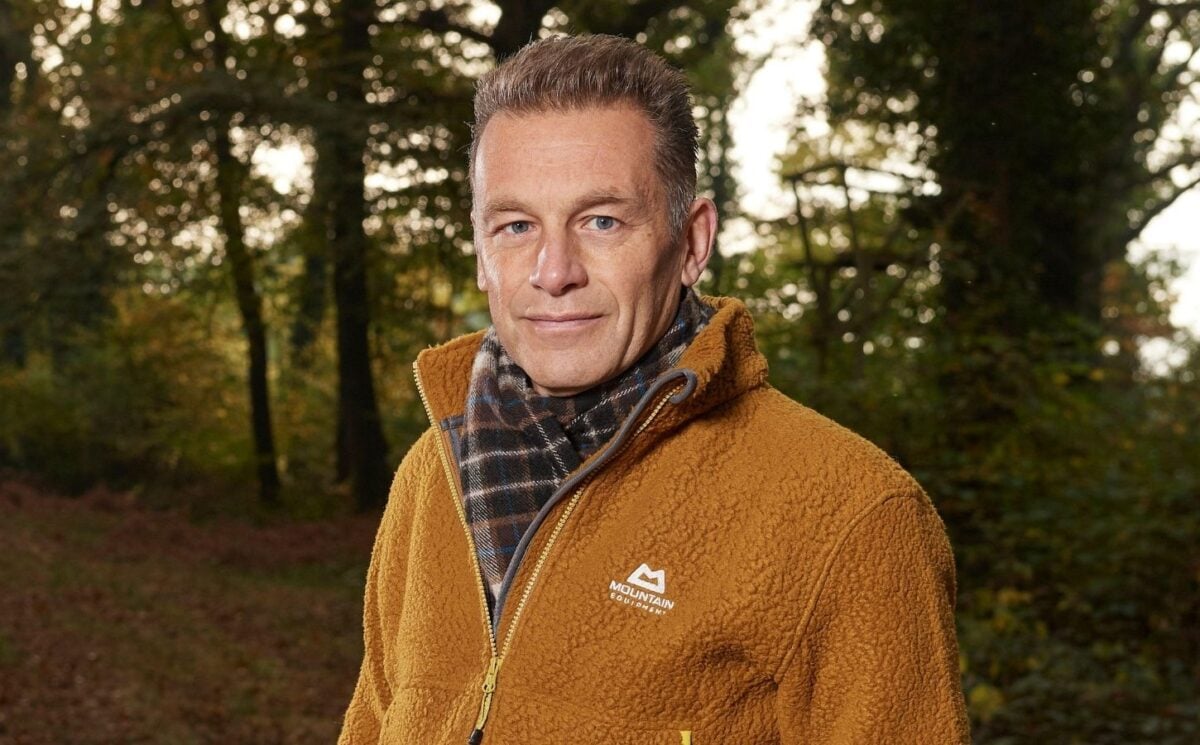 Photo shows Chris Packham standing in a woodland clearing