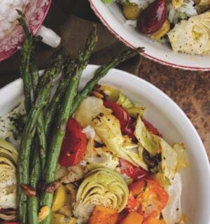 a picture of a cilantro veggie rice bowl topped with asparagus, artichoke, olives, cabbage, and tahini dressing