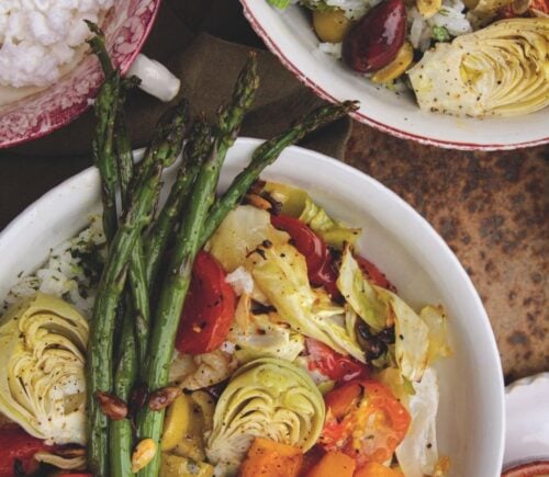 a picture of a cilantro veggie rice bowl topped with asparagus, artichoke, olives, cabbage, and tahini dressing