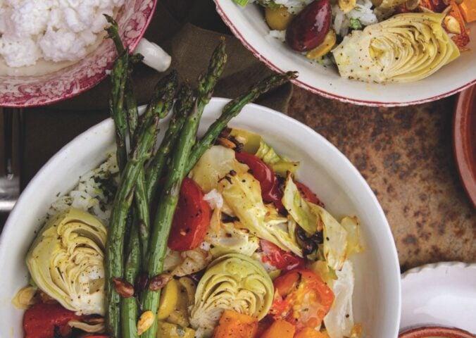 a picture of a cilantro veggie rice bowl topped with asparagus, artichoke, olives, cabbage, and tahini dressing