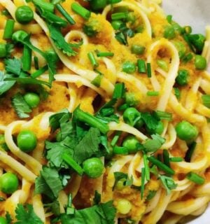 a picture of a curried carrot pasta topped with peas and cilantro