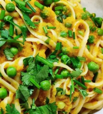 a picture of a curried carrot pasta topped with peas and cilantro