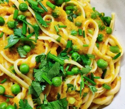 a picture of a curried carrot pasta topped with peas and cilantro