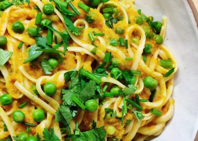 a picture of a curried carrot pasta topped with peas and cilantro