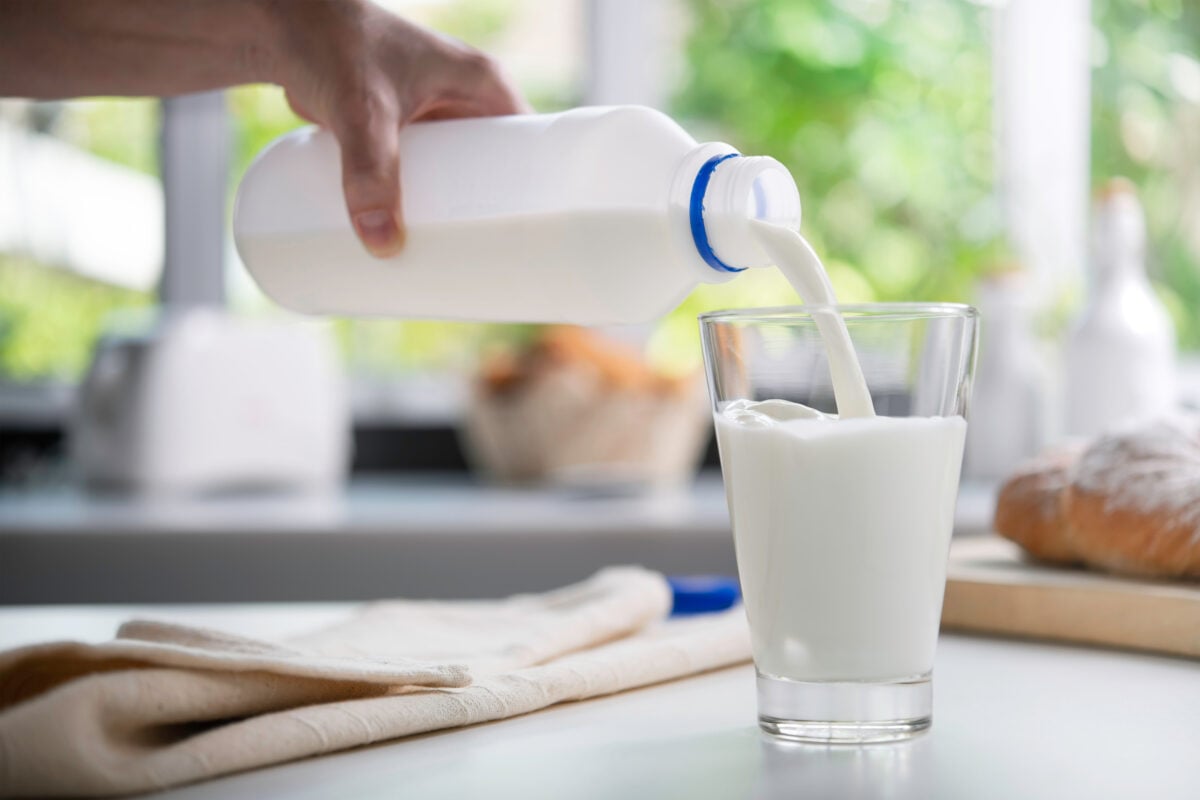 A person pouring a glass of milk, which is recommended by US dietary guidelines