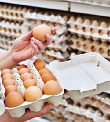 A person holding up an egg in a supermarket, many of whom have been recalled in the US due to a salmonella outbreak