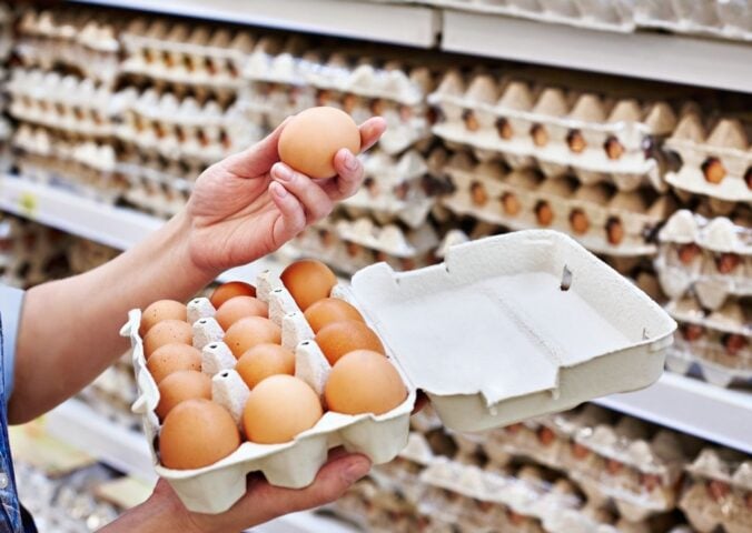 A person holding up an egg in a supermarket, many of whom have been recalled in the US due to a salmonella outbreak