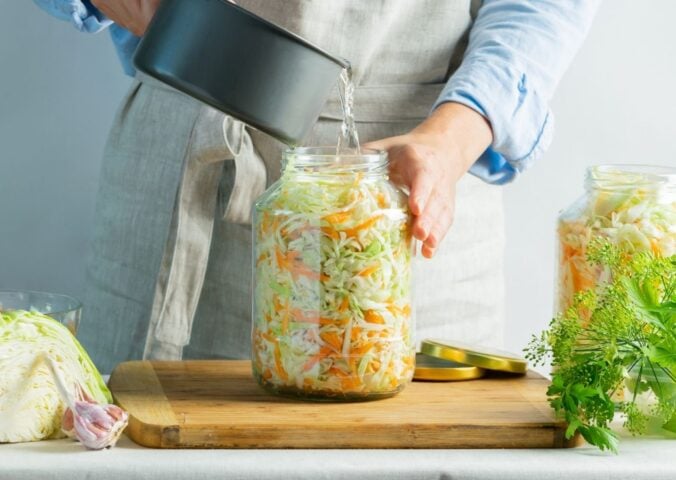 A woman making sauerkraut, a fermented food that benefits gut health