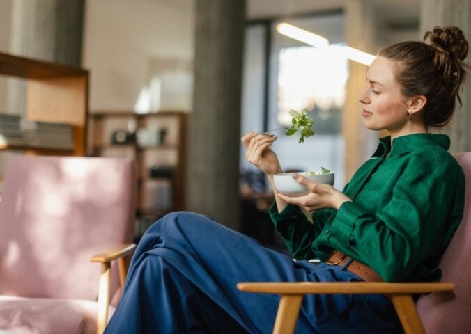 A woman eating a bowl of leafy salad including watercress, which is sometimes regarded as the healthiest vegetable