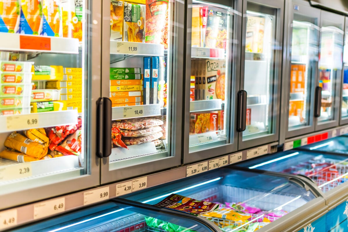 Photo shows refrigerators and freezers stocked with prep-prepared and packaged foods like pizzas and ready meals