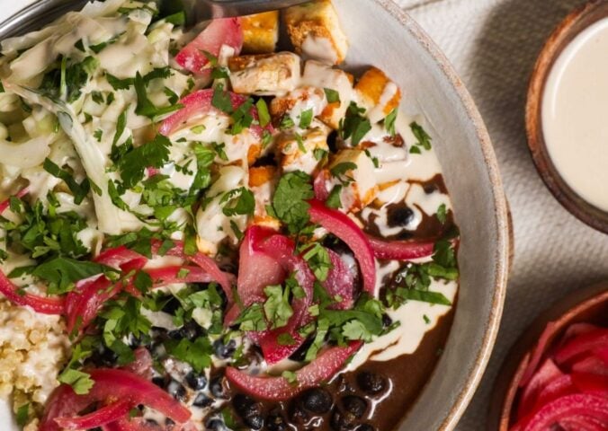 a picture of a protein packed bowl filled with quinoa, black beans, smoky tofu, and cabbage