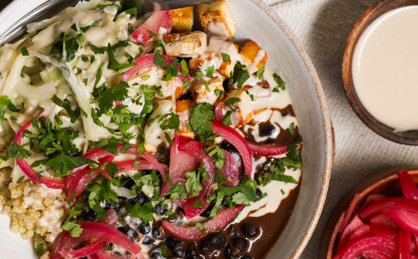 a picture of a protein packed bowl filled with quinoa, black beans, smoky tofu, and cabbage