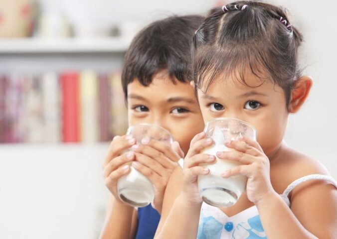 Two children drinking dairy milk in line with USDA dietary guidelines