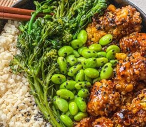 a picture of a tasty-as-takeout teriyaki cauliflower bowl made with heart of palm rice, teriyaki cauliflower, edamame, and broccolini