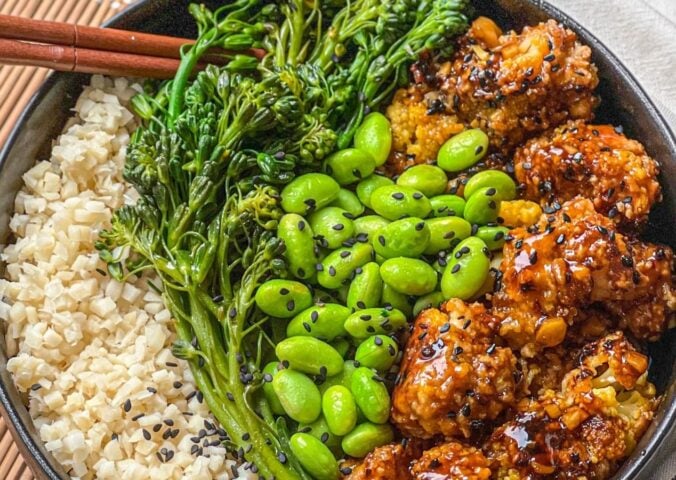 a picture of a tasty-as-takeout teriyaki cauliflower bowl made with heart of palm rice, teriyaki cauliflower, edamame, and broccolini