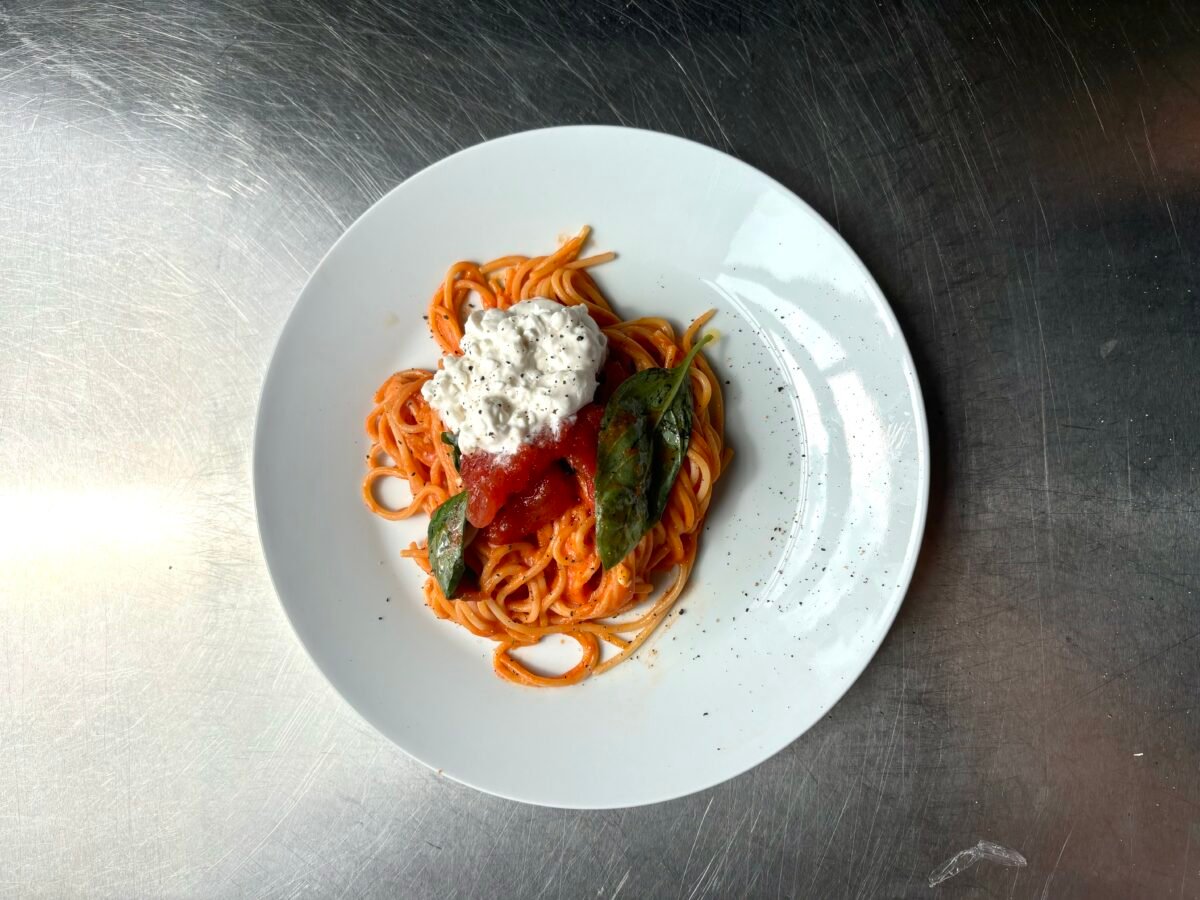 Photo shows a tomato-based pasta dish topped with JULIENNE BRUNO's vegan cheese, now available at Tesco Ireland