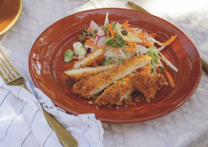 a picture of crispy tofu schnitzel topped with an apple coleslaw and dressing