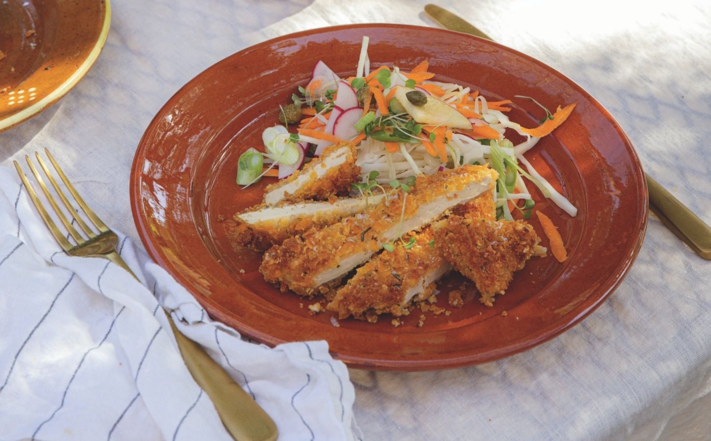 a picture of crispy tofu schnitzel topped with an apple coleslaw and dressing