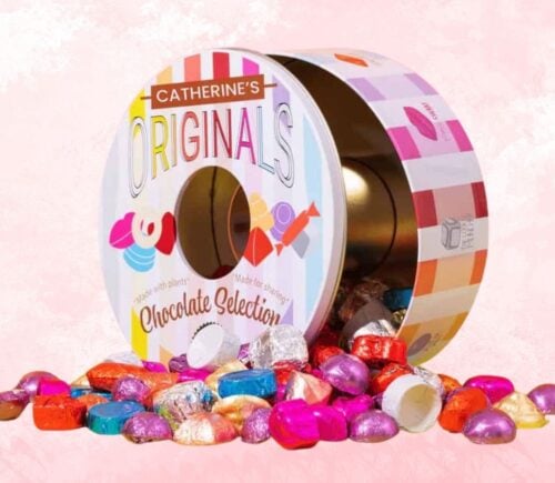 A tin of Catherine's Originals vegan chocolate selection tin in front of a pink background