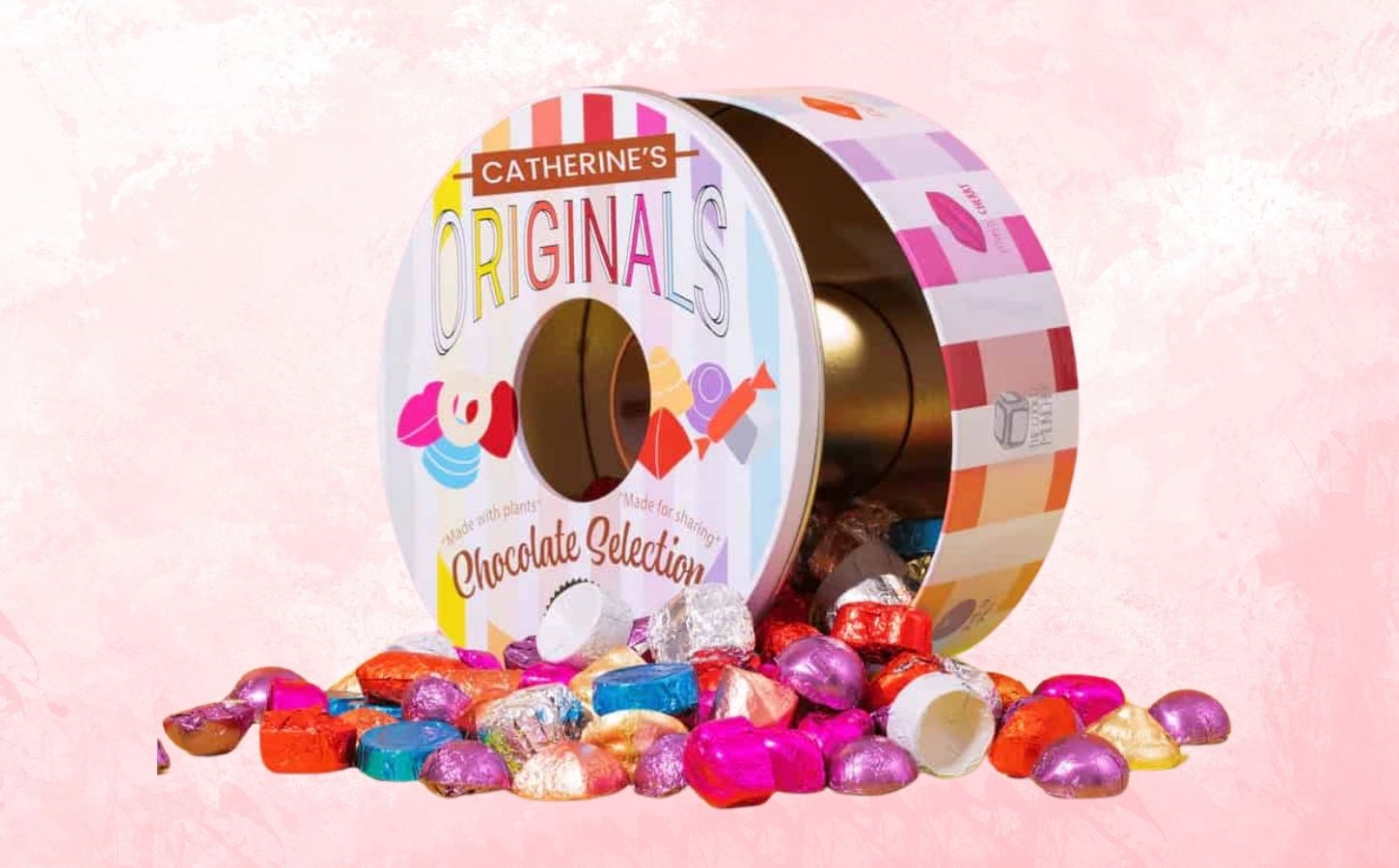 A tin of Catherine's Originals vegan chocolate selection tin in front of a pink background