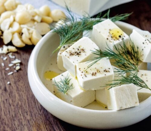 A white bowl filled with homemade macadamia feta, a homemade vegan cheese recipe cooked from scratch