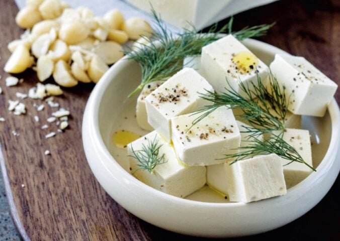 A white bowl filled with homemade macadamia feta, a homemade vegan cheese recipe cooked from scratch