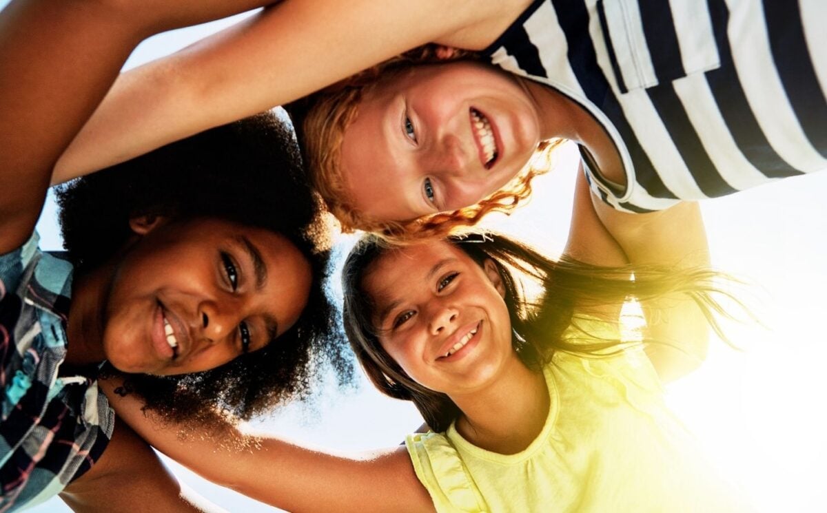 Three kids in a huddle outside in the sun