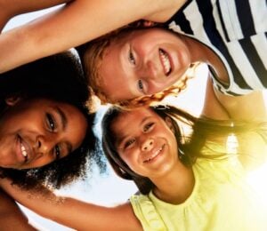 Three kids in a huddle outside in the sun