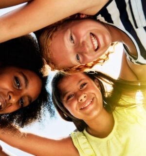 Three kids in a huddle outside in the sun