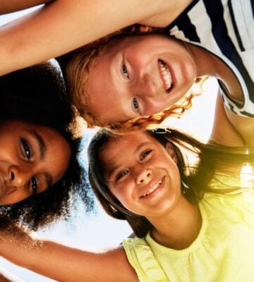 Three kids in a huddle outside in the sun