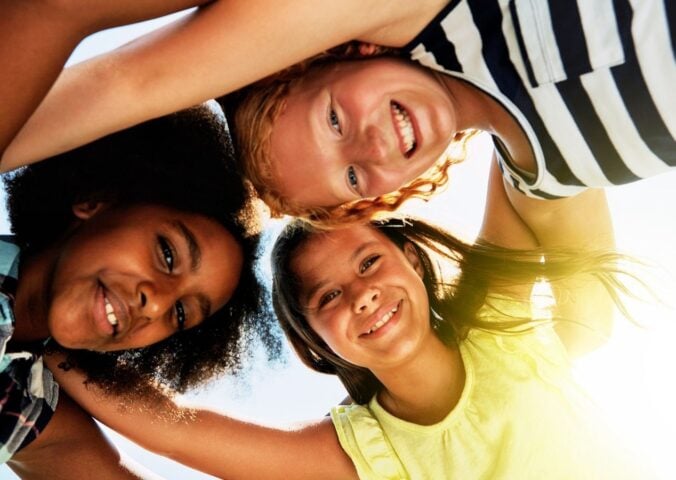 Three kids in a huddle outside in the sun