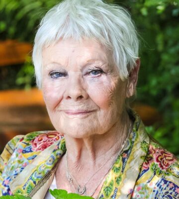 Photo shows actor Dame Judi Dench outdoors holding some green leaves