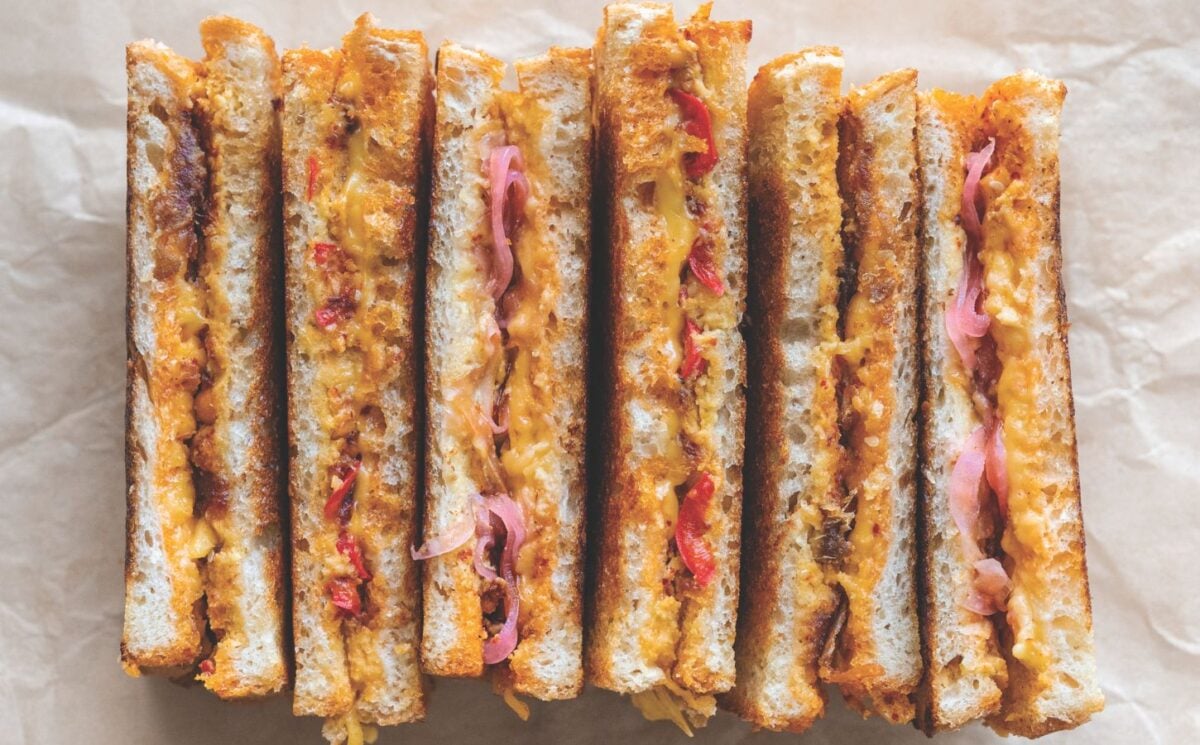 a picture of several vegan grilled cheese sandwiches paired with chili crisp. pickled onions, and more