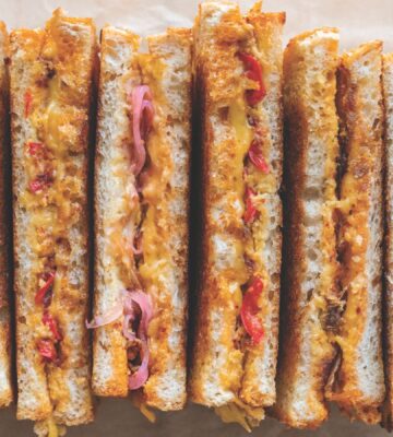 a picture of several vegan grilled cheese sandwiches paired with chili crisp. pickled onions, and more