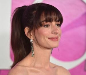 Actor Anne Hathaway on the red carper in front of a pink backdrop