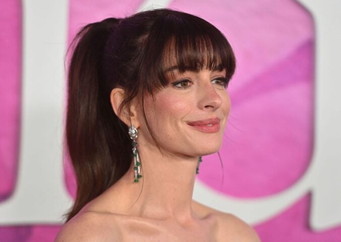 Actor Anne Hathaway on the red carper in front of a pink backdrop