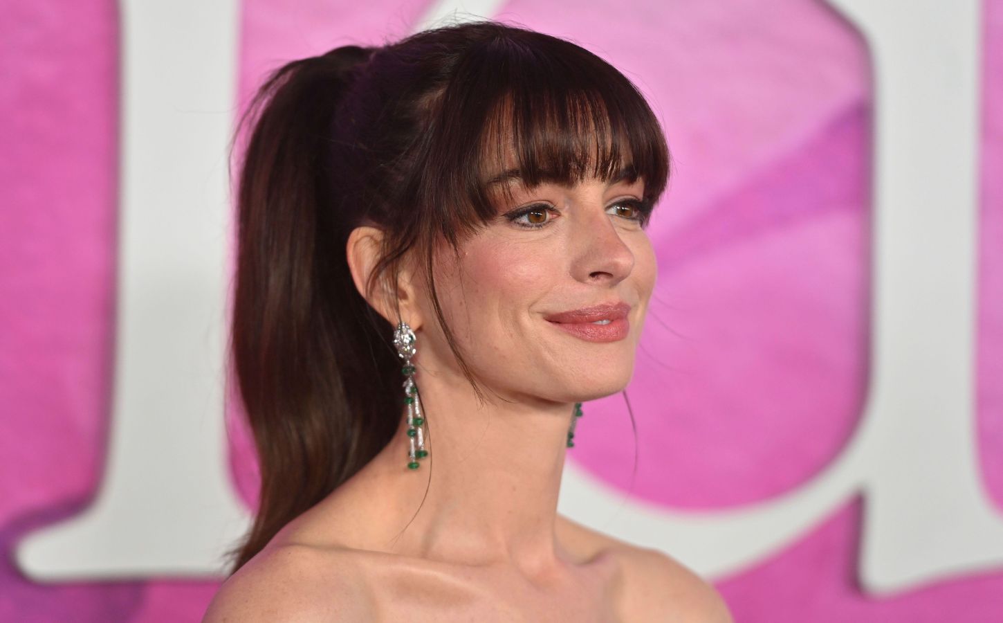 Actor Anne Hathaway on the red carper in front of a pink backdrop