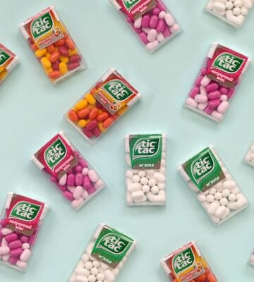 Photo shows a selection of Tic Tac boxes in different flavors and colors on a pale blue background