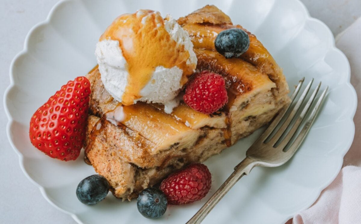 a picture of a slice of banana Tarte Tatin French toast topped with vegan ice cream, maple syrup and berries