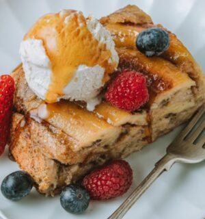 a picture of a slice of banana Tarte Tatin French toast topped with vegan ice cream, maple syrup and berries