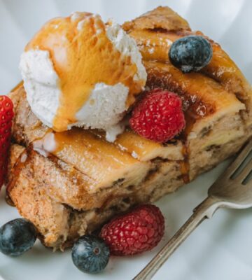 a picture of a slice of banana Tarte Tatin French toast topped with vegan ice cream, maple syrup and berries