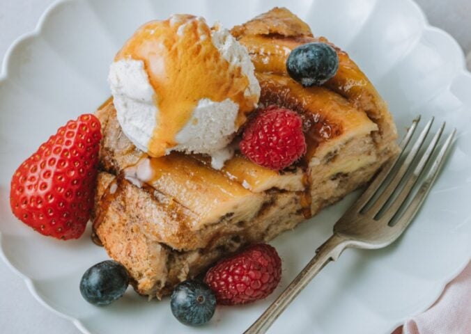 a picture of a slice of banana Tarte Tatin French toast topped with vegan ice cream, maple syrup and berries