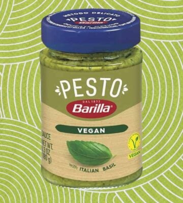 A jar of Barilla vegan pesto in front of a green patterned background