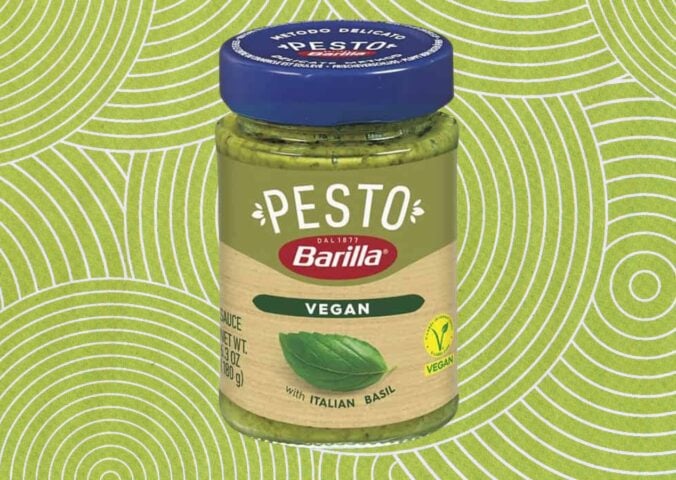 A jar of Barilla vegan pesto in front of a green patterned background