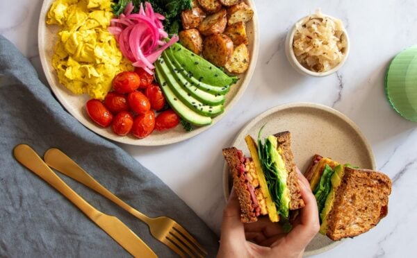 a picture of a vegan big breakfast sandwich made with tempeh, vegan egg, avo, and spinach