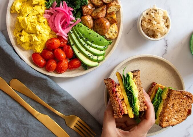 a picture of a vegan big breakfast sandwich made with tempeh, vegan egg, avo, and spinach