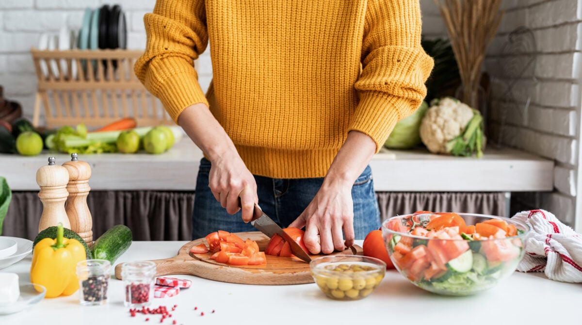 A woman cutting up plant-based food in a kitchen