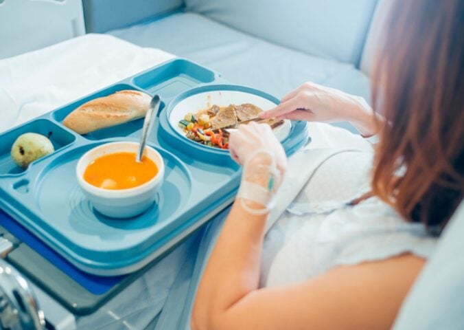 woman eating in hospital bed