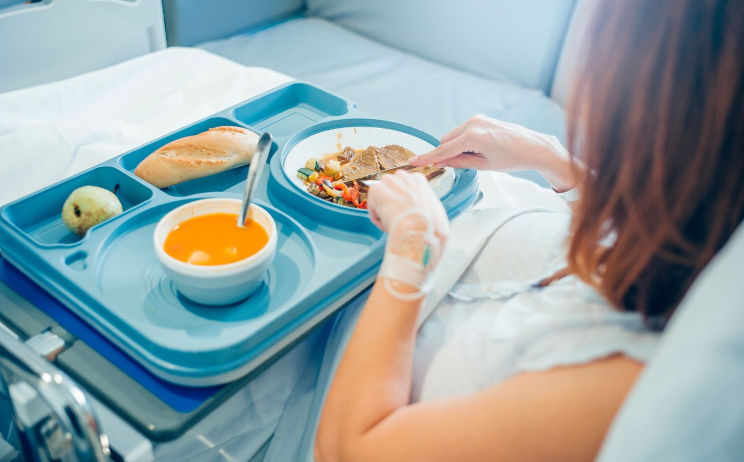 woman eating in hospital bed