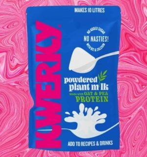 A packet of powdered vegan milk from KWERKY in front of a pink patterned background